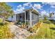 Exterior view of the backyard with a screened-in patio, manicured lawn, garden, and white fencing at 1181 Southland Rd, Venice, FL 34293