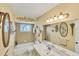 Charming bathroom featuring a tub, tiled walls, an oval mirror, and unique ornate lighting at 1181 Southland Rd, Venice, FL 34293