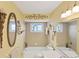 Bathroom featuring decorative mirrors and lighting fixtures, a tiled shower-bath, and a single-sink vanity at 1181 Southland Rd, Venice, FL 34293