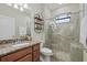 Bathroom with a tiled shower, glass doors, granite countertops, and wood cabinets at 12279 Canavese Ln, Venice, FL 34293