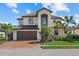 Beautiful two-story home featuring a tile roof, manicured lawn, and lush tropical landscaping at 12279 Canavese Ln, Venice, FL 34293