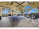 A covered outdoor patio with a ping pong table and seating overlooking palm trees at 12279 Canavese Ln, Venice, FL 34293