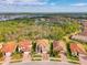 Aerial view of home with tile roof and brick driveway, near a lake, surrounded by lush greenery at 12410 Cinqueterre Dr, Venice, FL 34293