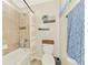 Cozy bathroom with a tub and shower combination and decorative shelving above the toilet at 12410 Cinqueterre Dr, Venice, FL 34293
