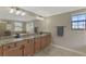 Bathroom featuring a double sink vanity and large mirror reflecting a tub and window at 12410 Cinqueterre Dr, Venice, FL 34293