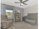 Bedroom with gray crib, bookshelf, and glider, featuring a calming blue accent wall at 12410 Cinqueterre Dr, Venice, FL 34293