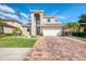 Front exterior view of the home, highlighting the brick driveway, tile roof, and neatly maintained lawn at 12410 Cinqueterre Dr, Venice, FL 34293