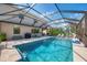 Large screened pool with travertine deck, basketball hoop, lounge chairs and outdoor kitchen at 12410 Cinqueterre Dr, Venice, FL 34293