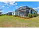 The backyard features a screened lanai with green shrubs and beautiful lawn area at 12505 Palatka Dr, Venice, FL 34293
