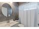 Bathroom with round mirror, gray floral wallpaper, and white shower curtain at 1298 Highland Greens Dr, Venice, FL 34285