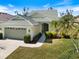 Charming single-story home featuring a light yellow exterior, well-manicured lawn, and a two-car garage with a beautiful garden at 1298 Highland Greens Dr, Venice, FL 34285