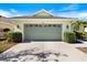 Garage front view featuring manicured landscaping, a neutral driveway, and carriage house doors with decorative windows at 1298 Highland Greens Dr, Venice, FL 34285
