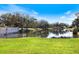 Scenic view of a tranquil pond surrounded by manicured green lawns and mature trees at 1298 Highland Greens Dr, Venice, FL 34285
