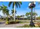 Charming street view with a clock tower, palm trees, businesses, and lush landscaping at 1298 Highland Greens Dr, Venice, FL 34285