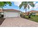 Home exterior featuring a brick driveway, two-car garage, and tropical landscaping on a sunny day at 13278 Huerta St, Venice, FL 34293