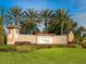 Community entrance sign for Venetian Falls featuring landscaping, palm trees, and a clear blue sky at 1342 Maseno Dr, Venice, FL 34292