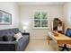 Office featuring a gray sofa, a wooden desk, and a window with plantation shutters at 1342 Maseno Dr, Venice, FL 34292