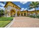 Grand clubhouse entrance with arched doorways, stone accents, lush landscaping, and brick-paved circular driveway at 13730 Vancanza, Venice, FL 34293