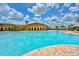 Stunning community pool featuring a zero entry, palm trees, and a community building in the background at 13730 Vancanza, Venice, FL 34293