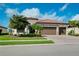 Home featuring a terracotta roof, a three car garage, nice landscaping and a manicured lawn at 13730 Vancanza, Venice, FL 34293