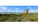 Scenic view of a lifeguard station on a sandy beach, framed by lush green dune grass and clear blue skies at 13730 Vancanza, Venice, FL 34293