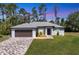 Single-story home featuring a two-car garage and well-manicured lawn at 1449 Overhead St, North Port, FL 34288