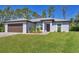 Charming single-story home featuring lush lawn, neutral paint, complemented by a brown garage door at 1449 Overhead St, North Port, FL 34288
