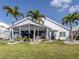 Charming home features a screened lanai, lush green lawn, and swaying palm trees, perfect for outdoor living at 1572 Jasper Ct, Venice, FL 34292