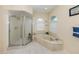 Bright bathroom featuring walk-in shower and marble garden tub under arched windows at 1572 Jasper Ct, Venice, FL 34292