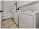 Bright laundry room features white washer and dryer, white cabinets and door with neutral tile flooring at 1572 Jasper Ct, Venice, FL 34292