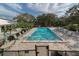 Beautiful in-ground pool surrounded by lounge chairs and mature trees under a sunny sky at 1572 Jasper Ct, Venice, FL 34292