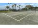 Outdoor tennis court with surrounding black net fencing, palm trees and blue skies at 1572 Jasper Ct, Venice, FL 34292