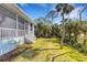 Backyard view features a screened lanai, lush greenery, and mature trees for added privacy at 1596 Landfall Dr, Nokomis, FL 34275