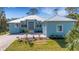 Charming single-story home with light blue exterior, manicured lawn, and a light-colored metal roof at 1596 Landfall Dr, Nokomis, FL 34275