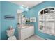 Bright bathroom features a blue accent wall, white vanity with granite counters, and a window with shutters at 1904 Canary Island St, Venice, FL 34292