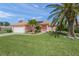 Charming pink single-story home with a tile roof, well-manicured lawn, and mature palm trees at 1904 Canary Island St, Venice, FL 34292