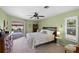 Spacious main bedroom with a ceiling fan, carpet flooring, and sliding door access to the pool at 1904 Canary Island St, Venice, FL 34292