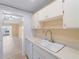 Kitchen featuring a large, single-basin sink with white cabinets and views of the living area at 200 The Esplanade N # B10, Venice, FL 34285