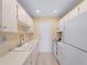 Galley kitchen with white appliances, ample cabinet space, and wood look floors at 200 The Esplanade N # B10, Venice, FL 34285
