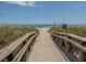 Beach access with wooden walkway leads to sandy shores and beautiful ocean views for beach enjoyment at 26825 Weiskopf Dr, Englewood, FL 34223