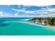Gorgeous aerial view of a sandy beach, turquoise water, and a scenic coastline with trees and parking at 397 Flamingo Dr, Venice, FL 34285