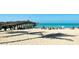 Tranquil beach scene with a pier, calm waters, and palm tree shadows on the sandy shore at 397 Flamingo Dr, Venice, FL 34285