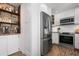 Charming kitchen featuring stainless steel appliances, white cabinetry, and distinctive brick flooring at 397 Flamingo Dr, Venice, FL 34285