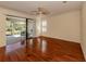 Living room with wood floors and fan, sliding glass doors to the screened lanai, and classic white shutters at 4238 Mackay Falls Ter, Sarasota, FL 34243