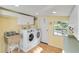 Bright laundry room with white cabinets, washer, dryer, and a stainless steel utility sink at 432 Palmetto Ct, Venice, FL 34285