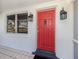 Close-up of a vibrant red front door framed by stylish sconces and a large window at 492 Constance Rd, Venice, FL 34293