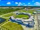 Aerial view of a baseball field with green grass, stadium seating, and parking lots, set against a background of trees and sky at 5194 Layton Dr, Venice, FL 34293