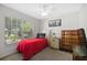Cozy bedroom with a red bedspread, natural light from the window, and classic furnishings at 5194 Layton Dr, Venice, FL 34293