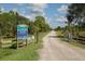 Deer Prairie Creek Preserve entrance with lush greenery and a gravel road under a sunny, partly cloudy sky at 5800 Niblick Pl, North Port, FL 34287