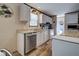 Bright kitchen with stainless steel dishwasher, white cabinets, and wood-look floors at 6665 Keystone Ct, North Port, FL 34287